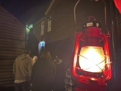 A red lantern lights up the foreground with a small crowd of people visible in the darker background.